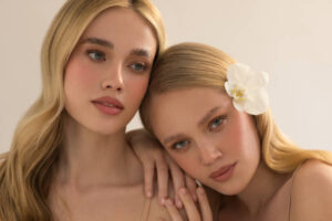 Portrait of two young woman with natural blonde hair. Well cared hair and skin. Sensual looks and elegant makeup.