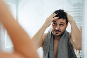 Happy man touching his wet hair while looking into the mirror in the morning.