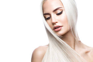 Beautiful blond girl in move with a perfectly smooth hair, and classic make-up. Beauty face. Picture taken in the studio.